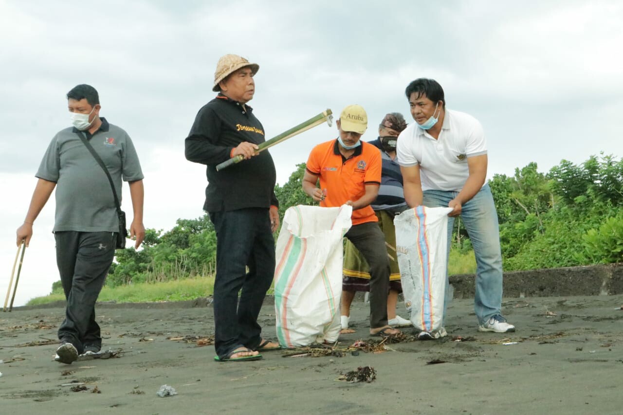 Bupati Jembrana I Nengah Tamba turut memungut sampah plastik dalam kegiatan menyambut Hari Air Sedunia 2022 yang dipusatkan di Pantai Perancak, Jembrana, Jumat (1/4). (Foto: Biro Humas Pemkab Jembrana)